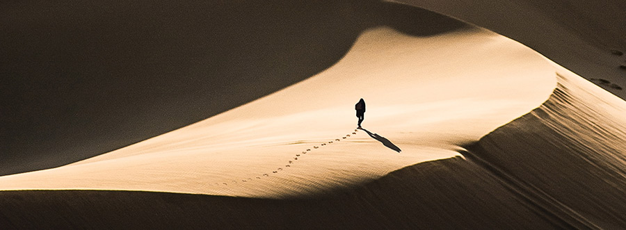 Photo of person at a distance walking through the desert