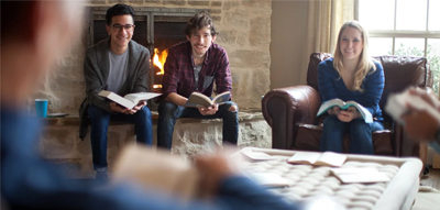 Group of students sitting next to a fire while reading books
