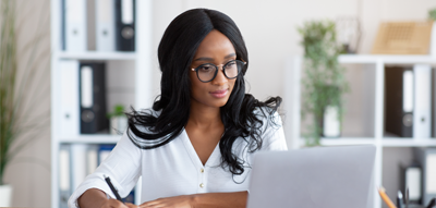 Black woman sitting at desk looking at computer