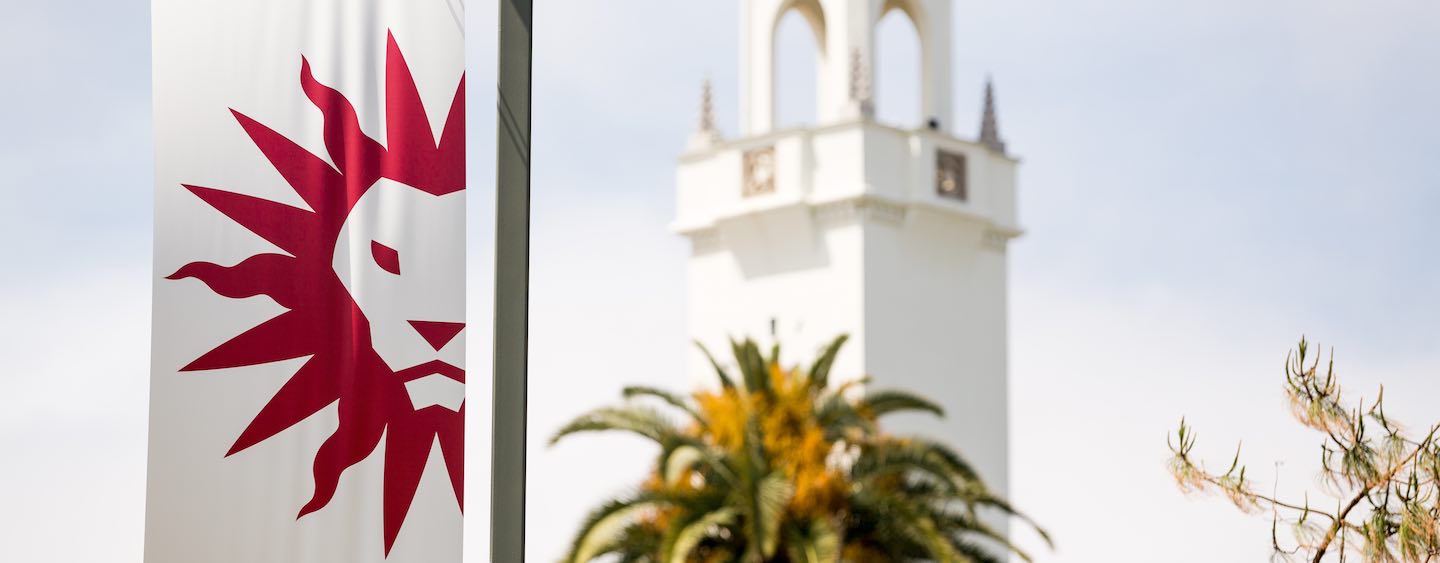 Street pole banner displaying LMU spirit mark with chapel tower and palm tree in background